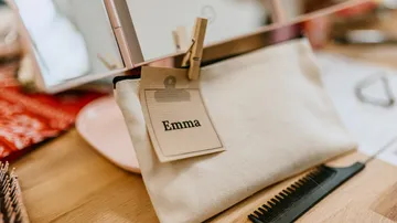 Weiße Tasche mit der Aufschrift „Emma“ mit Kamm in der Nähe.