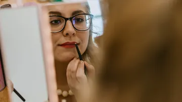 Frau trägt Lippenstift im Spiegel auf.