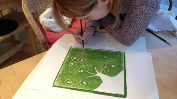 Person, die ein grünes Baumdesign auf Papier malt.