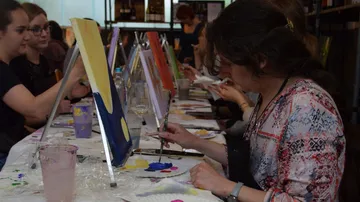 People painting on canvases at a workshop.
