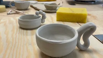 Unfinished ceramic mugs on wooden table.