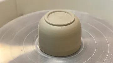 Clay bowl upside down on pottery wheel.