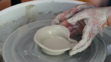 Hände formen Tonschale auf Töpferscheibe.