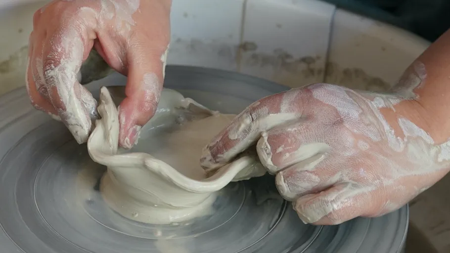 Hands shaping clay on a pottery wheel.