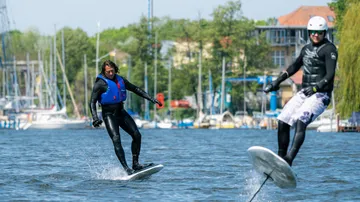 Two people on e-foils in a marina.