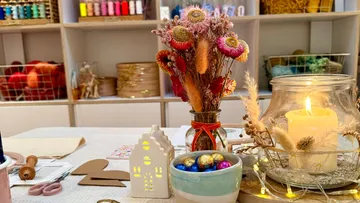 Basteltisch mit Blumen und Kerzen, bunt eingerichtet.