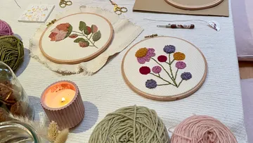 Embroidery hoops with floral designs on table.
