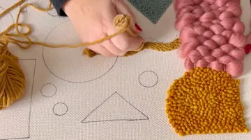 Handwebgarn auf Leinwand mit geometrischem Muster.