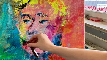 Hand mit Spachtel auf buntem Portrait.