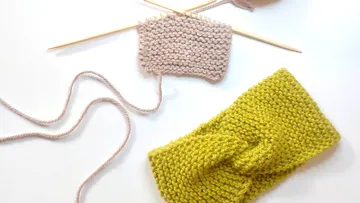 Knitted headband and yarn on needles.
