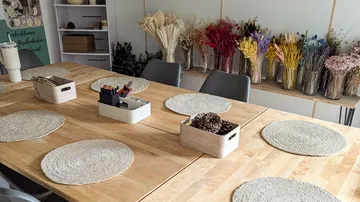Basteltisch mit Tannenzapfen, Matten und Vasen.