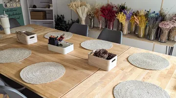 Holztisch mit Tischsets und Vasen mit Trockenblumen.