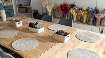 Basteltisch mit Tischsets aus Korbgeflecht und bunten Blumen.