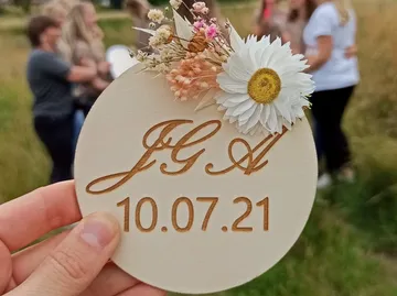 Hält eine mit Blumen verzierte Karte mit Datumsaufschrift in der Hand.