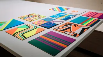 Bunte geometrische Kunstwerke, angeordnet auf einem weißen Tisch.