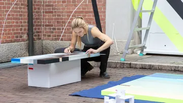 Künstler bemalt eine Bank im Freien.