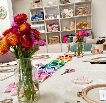 Basteltisch mit Stickereibedarf und Blumen.