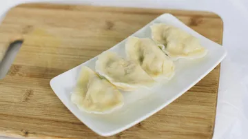 Vier gedämpfte Knödel auf einem weißen Teller.