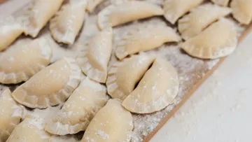 Ungekochte Knödel, auf einem bemehlten Brett angeordnet.