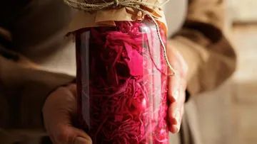 Person holding jar of pickled red cabbage.