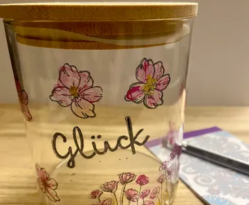 Glass jar with 'Glück' and flower designs.