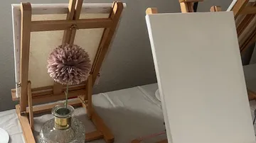 Blank canvases on easels with flower vase.