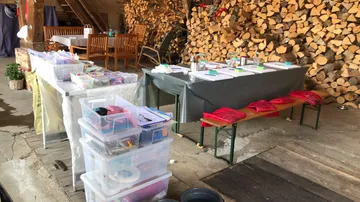 Bastelbedarf, angeordnet auf Tischen in einer rustikalen Umgebung.