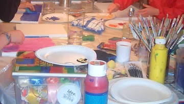 Kinder malen mit Malutensilien auf dem Tisch.