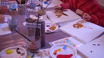 Kinder malen Leinwände am Kunsttisch.