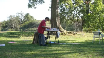 Person, die auf einem Tisch in einem sonnigen Park malt.