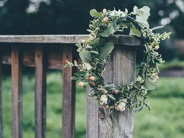 Wreath hangs on a wooden fence in a green environment.