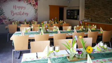 Geschmückte Tische mit Blumen für die Geburtstagsfeier.