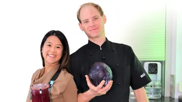 Two chefs smiling with a cabbage and jar.