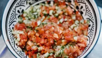 Colorful diced vegetables in patterned bowl.