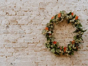 Green wreaths adorn a white, rough brick wall.