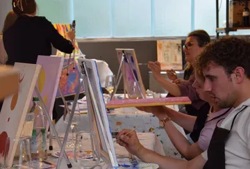 People painting on canvases in art class.