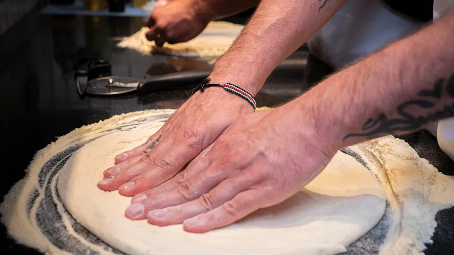 Hands shaping dough on floured surface.