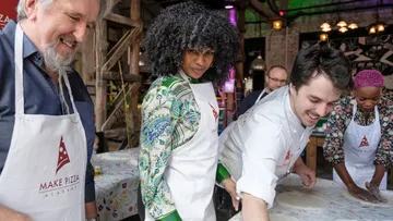 People making pizza in a workshop setting.