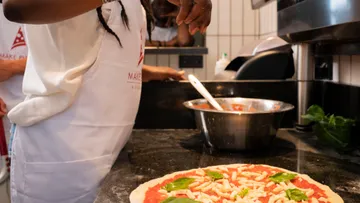 Person preparing pizza in kitchen.