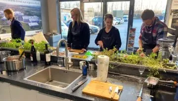 People cooking at a kitchen countertop.