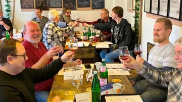 Men toasting with red drinks in meeting room.