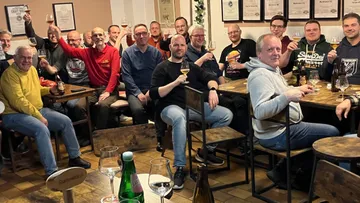 Group of people toasting with drinks in a room.