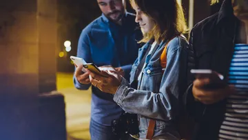 Leute, die nachts draußen Smartphones benutzen.