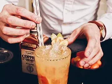 Ein Cocktail wird mit einem Strohhalm garniert, Tisch.