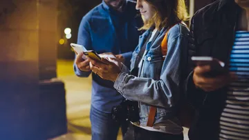 People using smartphones outdoors at night.
