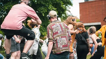 People dancing outdoors wearing headphones.