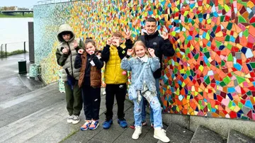 Gruppe posiert an einer bunten Mosaikwand