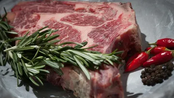 Raw steak with rosemary and spices.