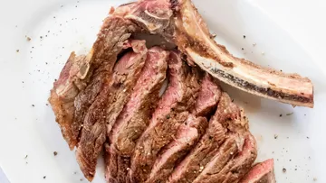 In Scheiben geschnittenes Ribeye-Steak mit Knochen auf Teller