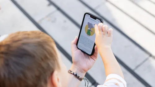Kind schaut sich im Freien Zeichentrickfilm auf dem Smartphone an.